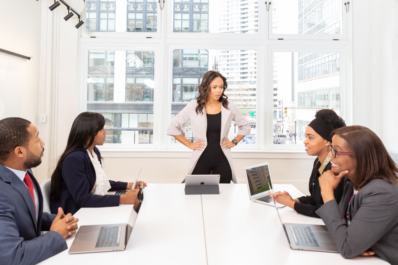 Mastering the First Impression: Your intriguing post title goes here A diverse group of professionals engaged in a meeting at a modern office with laptops and city view.