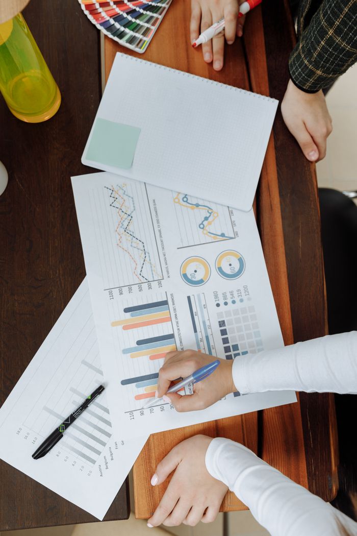 The Art of Drawing Readers In: Your attractive post title goes here Top view of business team analyzing charts and data on paper for strategic planning.