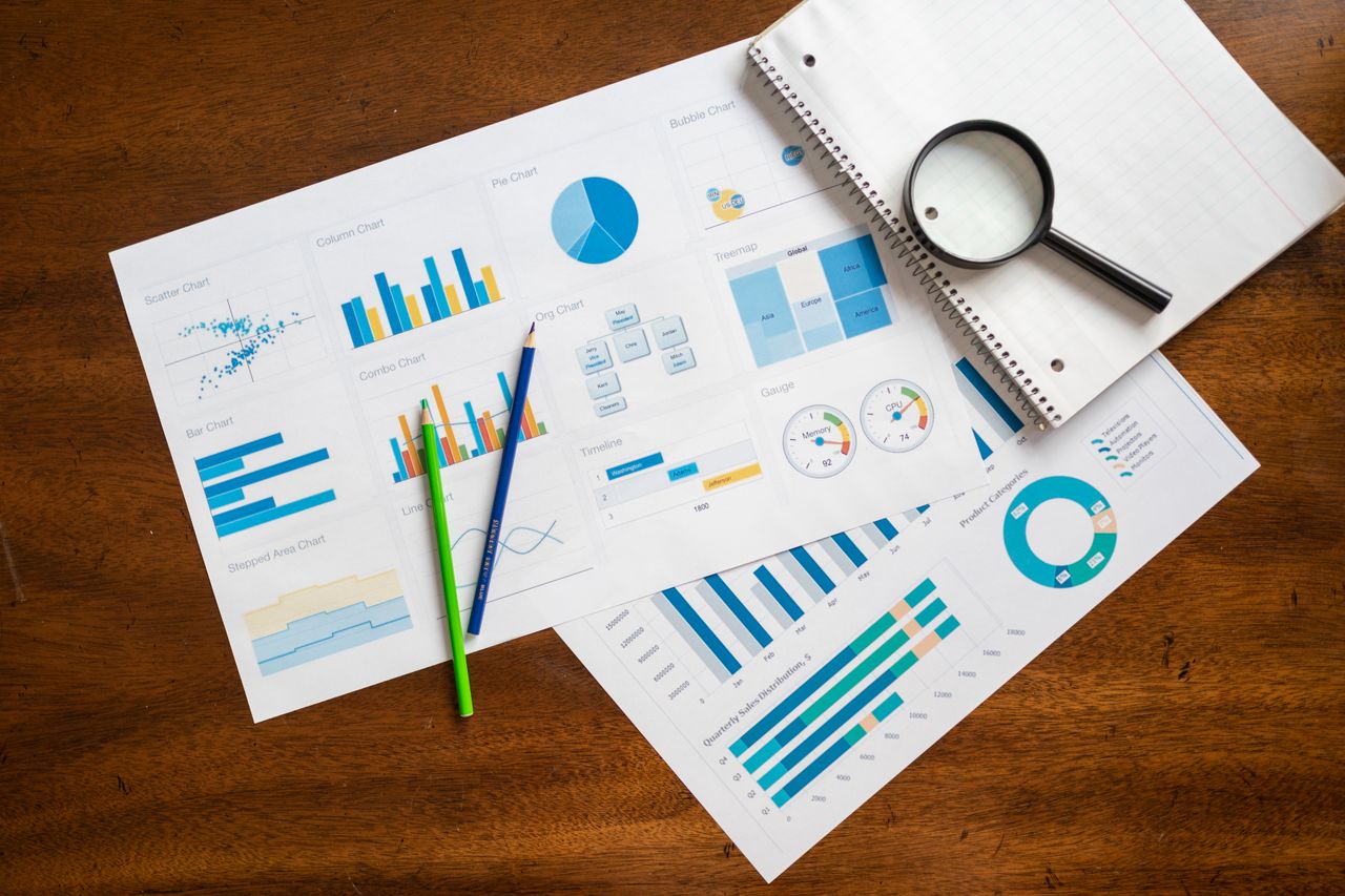 Services Overhead view of financial charts, magnifying glass, and stationery on wooden table.